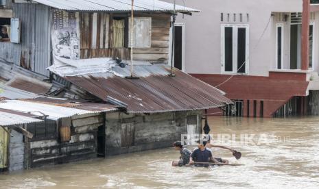 Anak laki-laki naik tabung melalui daerah pemukiman banjir di Medan, Sumatera Utara, Indonesia, 05 Desember 2020.