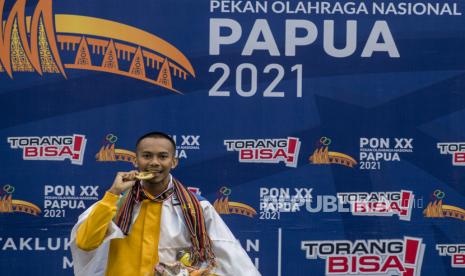 Atlet lompat jauh putra Nusa Tenggara Barat Sapwaturrahman mengigit medali emasnya saat penerimaan medali Lompat Jauh Putra PON Papua di Stadion Atletik Mimika Sport Center, Kabupaten Mimika, Papua, Selasa (5/10/2021). Sapwaturrahman meraih medali emas sementara medali perak diraih atlet Sumatera Utara  Shafwan Hafizah dan medali perunggu diraih atlet Kepulauan Bangka Belitung Suwandi Wijaya. 