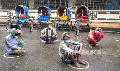 Bangladesh Longgarkan Aturan Covid-19 pada Idul Adha. Orang-orang Bangladesh duduk di jalan saat mereka menunggu untuk menerima makanan gratis yang disediakan oleh Polisi Metropolitan Dhaka selama penguncian keras di Dhaka, Bangladesh, 7 Juli 2021. Pihak berwenang Bangladesh memberlakukan penguncian habis-habisan secara nasional selama seminggu di tengah meningkatnya infeksi virus corona dan Covid -19 kematian terkait di negara ini.