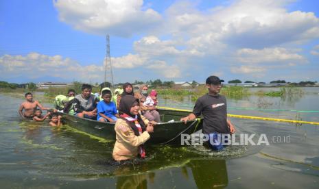 Warga menggunakan perahu melintasi jalan yang terdampak banjir di Karangturi, Setrokalangan, Kaliwungu, Kudus, Jawa Tengah.