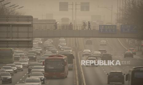 Orang-orang berjalan melintasi jembatan penyeberangan di kawasan pusat bisnis di Beijing, Rabu (22/3/2023). Badai debu dan pasir membuat indeks kualitas udara melonjak di ibu kota China pada Rabu pagi.