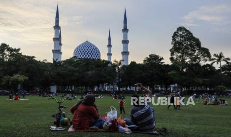 Malaysia Siapkan Masjid Sebagai Pusat Penanganan Korban KDRT. Foto:  Muslim Malaysia menjaga jarak sosial dan mengenakan masker pelindung wajah saat mereka menunggu berbuka puasa di depan masjid di taman umum di Shah Alam, di luar Kuala Lumpur, Malaysia, 25 April 2021. 