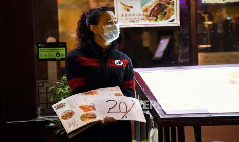 Seorang pelayan dengan menggunakan masker menunggu pembeli di sebuah  restoran di Soho, London, Selasa (22/9). Perdana Menteri Inggris Boris Johnson mengumumkan bahwa tempat pub dan restoran akan tutup pada pukul 10 malam hal ini akibat karena lonjakan kasus Covid-19 di seluruh Inggris Raya.  AP Photo/Alberto Pezzali