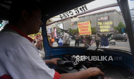 Sopir bajaj melihat massa yang tergabung dalam Aliansi Rakyat Menggugat membawa poster berunjuk rasa anti pemilu curang di depan Gedung Bawaslu, Jakarta, Rabu (10/1/2024). Dalam aksinya mereka meminta kepada penyelenggara dan pengawas pemilu bersikap netral dan tidak terintervensi dari pihak manapun. 