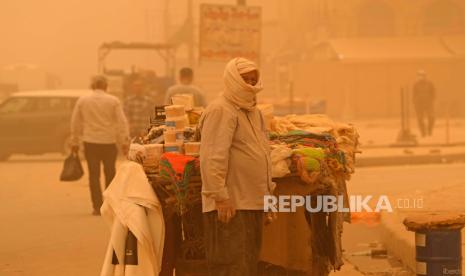 Seorang pedagang kaki lima menunggu pelanggan selama badai pasir di Baghdad, Irak, Senin, 16 Mei 2022. Badai Pasir Diprediksi Kembali Selimuti Riyadh