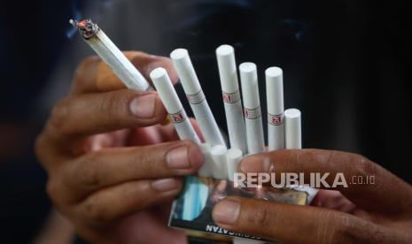 Seorang pria merokok sambil menunjukkan batang rokok di sebuah jalan di Jakarta, Indonesia, 27 Desember 2022. Presiden Indonesia Joko Widodo telah mengeluarkan Keputusan Presiden Republik Indonesia tentang program penyusunan peraturan pemerintah tahun 2020, salah satunya adalah menetapkan a larangan penjualan batang rokok, larangan zat adiktif pada produk tembakau bagi kesehatan.