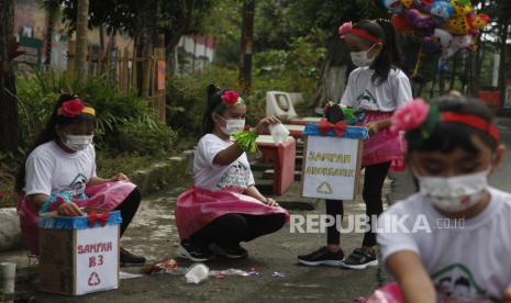 Sejumlah anak memungut sampah di lingkungan perumahan warga Joho Kampoeng Hepi, Manahan, Solo, Jawa Tengah, Ahad (23/1/2022). Kegiatan bertajuk Papi Sarimah atau Paksa Pilah Sampah dari Rumah tersebut sebagai kampanye membuang sampah pada tempatnya dan edukasi pemilahan sampah organik dan non organik bagi warga setempat.