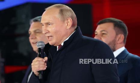 Presiden Rusia Vladimir Putin berbicara saat Leonid Pasechnik, pemimpin Republik Rakyat Luhansk yang memproklamirkan diri, kiri, dan Denis Pushilin, pemimpin Republik Rakyat Donetsk yang memproklamirkan diri, kanan, berdiri di dekatnya selama perayaan menandai penggabungan wilayah Ukraina ke bergabung dengan Rusia di Lapangan Merah dengan Menara Spasskaya di sebelah kanan, di Moskow, Rusia, Jumat, 30 September 2022. Penandatanganan perjanjian yang menjadikan empat wilayah bagian dari Rusia mengikuti penyelesaian yang diatur oleh Kremlin