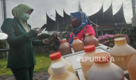 Seorang pedagang jamu keliling, melakukan transaksi digital melalui QRIS dengan pelanggannya, di Padang, Sumatera Barat, Selasa (3/11/2020). Otoritas Jasa Keuangan (OJK) memastikan keamanan transaksi digital perbankan terjaga pada masa pandemi COVID-19, sejalan dengan  langkah regulator yang melakukan evaluasi keamanan terhadap industri jasa keuangan. 