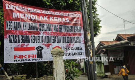 Warga melintas di samping spanduk penolakan kegiatan pendidikan Khilafatul Muslimin di Pekayon, Bekasi, Jawa Barat, Rabu (15/6/2022).  Kementerian Agama tegaskan Pesantren Khilafatul Muslimin tidak terdaftar dan tidak memiliki nomor statistik Pesantren atau Lembaga Keagamaan Islam.