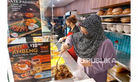 Manajer Restoran Masakan Padang Putra Minang di Bencoolen Street, Singapura, Dina, ketika melayani pengunjung. Ia mewajibkan penggunaan masker saat pengambilan makanan untuk menjaga keamanan dari bahaya virus Covid-19.