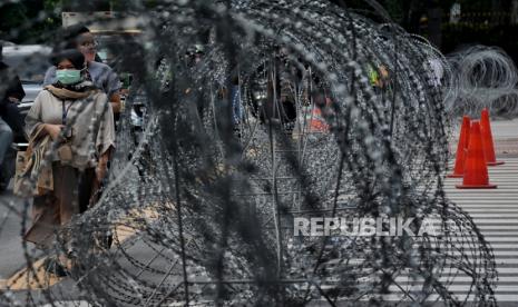 Warga berjalan di depan lokasi penutupan Jalan M.H Thamrin, Jakarta (2/12). Penutupan akses jalan menuju Monumen Nasional (Monas) dan Patung Kuda tersebut dilakukan sebagai antisipasi kerumunan peserta massa aksi Reuni 212.  Republika/Thoudy Badai