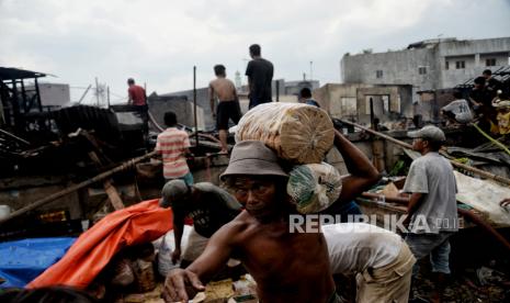 Warga membawa barang yang selamat dari api yang mengahanguskan beberapa rumah di kawasan pemukiman padat penduduk Kramat Pulo, Senen, Jakarta, Rabu (15/12). Sebanyak 17 mobil pemadam kebakaran dikerahkan untuk memadamkan api yang menghanguskan permukiman warga. Kebakaran terjadi pada pukul 08.37 WIB diduga akibat korsleting listrik yang menyebabkan sekitar 25 petak rumah hangus terbakar. 