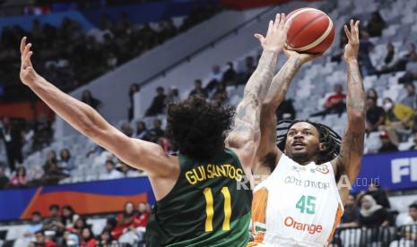 Pebasket Pantai Gading Nisre Zouzoua (kanan) berusaha menembak bola dihadang pebasket Brasil Gui Carvalho (kiri) dalam laga terakhir grup G FIBA World Cup 2023 di Indonesia Arena, Gelora Bung Karno, Jakarta, Rabu (30/8/2023).