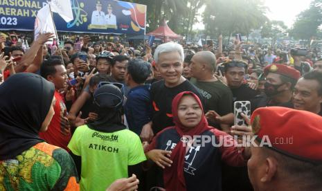 Gubernur Jawa Tengah Ganjar Pranowo (tengah) didampingi istri Siti Atikoh Supriyanti (kedua kiri) melayani warga berswafoto saat berolahraga di Alun-alun Jember, Jawa Timur, Ahad (7/5/2023). Bakal calon presiden yang diusung PDI Perjuangan itu mengunjungi Jember sambil berolahraga dan menyapa warga. 