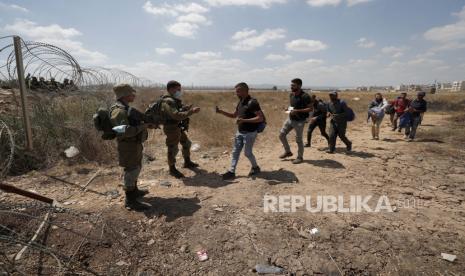  Pasukan keamanan Israel memeriksa identitas warga Palestina saat mereka mengantre dalam perjalanan kembali ke kota Jenin, Tepi Barat, melalui celah di pagar keamanan, dekat desa Israel Muqabla, 06 September 2021. Sejumlah tahanan keamanan melarikan diri dari Penjara Gilboa, kata Kantor Perdana Menteri Israel pada 06 September.