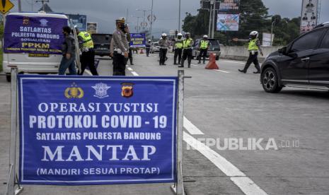 [Ilustrasi] Anggota Satlantas Polresta Bandung memberhentikan kendaraan saat operasi penyekatan dan pemeriksaan di Gerbang Keluar Jalan Tol Soreang, Kabupaten Bandung, Ahad (31/1). Operasi penyekatan dan pemeriksaan bagi setiap kendaraan luar daerah yang masuk ke Kabupaten Bandung tersebut digelar dalam rangka Penerapan Pembatasan Kegiatan Masyarakat (PPKM) guna mencegah penyebaran Covid-19 di wilayah Kabupaten Bandung yang saat ini berstatus zona merah Covid-19. Foto: Abdan Syakura/Republika