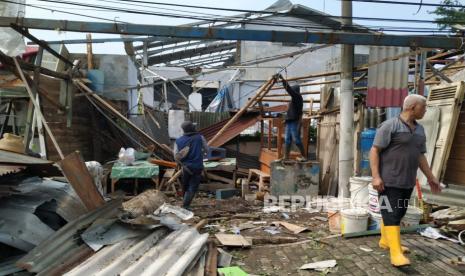 Warga bersama petugas dari unsur terkait berupaya membereskan bangunan dan pohon-pohon tumbang akibat angin puting beliung yang terjadi di Jalan Rancaekek, Kabupaten Bandung, Kamis (22/2/2024). Menurut Pakar klimatologi di Badan Riset dan Inovasi Nasional (BRIN), mengatakan, angin kencang yang merusak banyak bangunan di Rancaekek  diduga jenis badai tornado. 