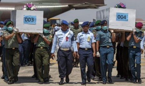 Indonesian military personnel carry caskets containing the remains of passengers onboard AirAsia flight QZ8501, recovered off the coast of Borneo, at a military base in Surabaya January 1, 2015.