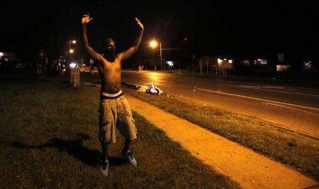  Seorang pengunjuk rasa mengangkat tangannya di Ferguson, Missouri, Senin (11/8).    (REUTERS/Mario Anzuoni)