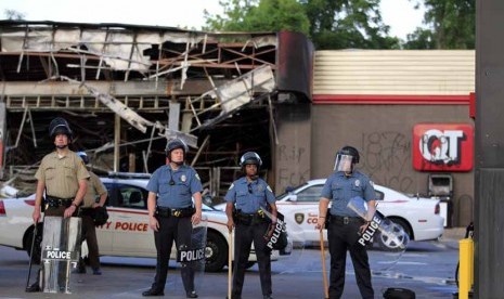  Pasukan polisi berjaga di depan bangunan super market yang dibakar massa di Ferguson, Missouri, Senin (11/8).    (AP/Jeff Roberson)