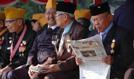  Seorang peserta membaca koran saat menanti upacara HUT Kemerdekaan ke-69 RI di Gasibu, Kota Bandung, Ahad (17/8). (Republika/Edi Yusuf)