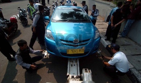 Officers tow an illegally parked taxis in Kalibata, South Jakarta on Monday. 