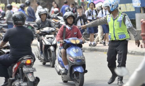  Seorang polisi menghentikan pelajar bersepeda motor saat penertiban pelajar pelanggar lalu lintas di Denpasar, Bali, Senin (8/9). (Antara/Nyoman Budhiana) 