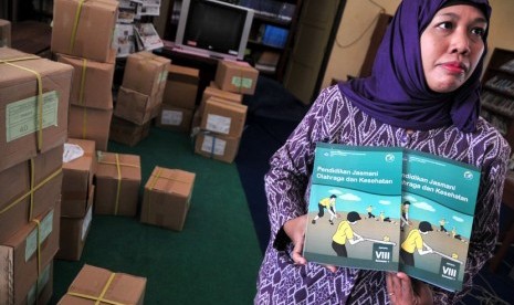 Seorang guru menunjukkan buku paket kurikulum 2013 mata pelajaran pendidikan jasmani olahraga dan kesehatan di SMPN 11 Tegal, Jateng, Selasa (9/9). 