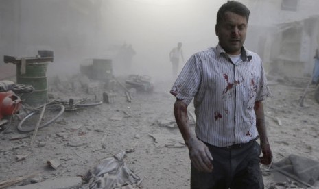   Seorang pria melintasi debu reuntuhan bangunan setelah serangan udara pasukan yang loyal kepada Presiden Bashar al-Assad di Duma, dekat kota Damaskus, Suriah, Kamis (11/9). (Reuters/Bassam Khabieh)