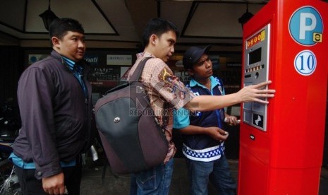   Pengendara dibantu juru parkir melakukan transaksi parkir dengan menggunakan mesin parkir meter di Jalan Sabang, Jakarta Pusat, Senin (6/10). (Republika/Raisan Al Farisi)