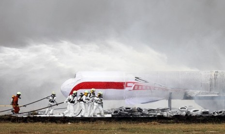 Sejumlah petugas pemadam kebakaran melakukan evakuasi penumpang yang selamat, saat simulasi penanggulangan keadaan darurat di Bandara Soekarno Hatta, Tangerang, Banten, Kamis (16/10).   (Antara/Muhammad Iqbal)