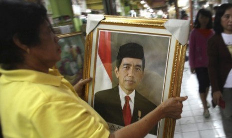 Seorang pedagang memegang foto Joko Widodo di Surabaya. 