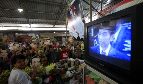   Sejumlah pedagang dan pengunjung mengenakan topeng bergambar Jokowi saat menonton bersama melalui TV acara pelantikan Presiden, Joko Widodo dan wakilnya, Jusuf Kalla di Pasar Gede, Solo, Jawa Tengah, Senin (20/10). (Antara/Maulana Surya)