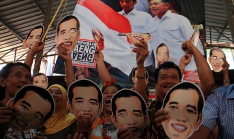   Sejumlah pedagang dan pengunjung mengenakan topeng bergambar Jokowi saat menonton bersama melalui TV acara pelantikan Presiden, Joko Widodo dan wakilnya, Jusuf Kalla di Pasar Gede, Solo, Jawa Tengah, Senin (20/10). (Antara/Maulana Surya)