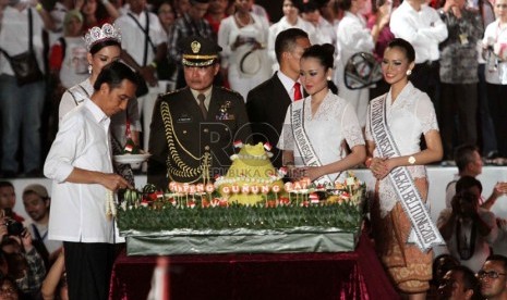  Presiden Jokowi memotong tumpeng pada Konser Salam 3 Jari di lapangan Monumen Nasional, Jakarta, Senin (20/10) malam.   (Republika/Yasin Habibi)