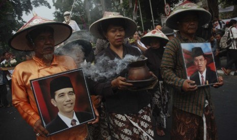 Sejumlah warga mengikuti prosesi kirab penyambutan Presiden ke-7 RI Jokowi di kawasan Nol Kilometer Yogyakarta, Senin (20/10).