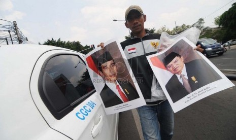   Seorang pedagang menjajakan poster Presiden Joko Widodo dan Wakil Presiden Jusuf Kalla di Kawasan Menteng, Jakarta Pusat, Senin (3/11). ( Republika/Raisan Al Farisi)