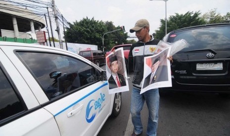   Seorang pedagang menjajakan poster Presiden Joko Widodo dan Wakil Presiden Jusuf Kalla di Kawasan Menteng, Jakarta Pusat, Senin (3/11). ( Republika/Raisan Al Farisi)