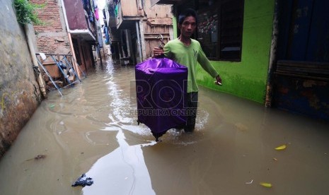   Seorang warga menyelamatkan burung peliharaannya saat banjir yang menggenangi Kawasan Kampung Pulo gang 5, Jakarta Timur, Selasa (11/11).  (Republika/Raisan Al Farisi)