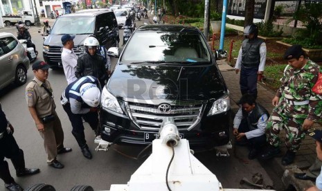   Petugas dari Dinas Perhubungan mengencangkan tali pengikat ban pada mobil yang ditertibkan di Jalan Kemang Raya, Jakarta Selatan, Rabu (26/11).  (Republika/Raisan Al Farisi)