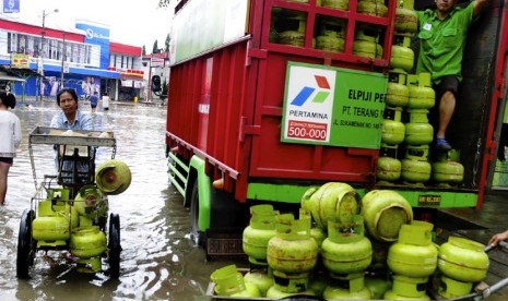   Warga membawa sejumlah tabung gas elpiji 3 kg melewati genangan banjir di Jalan Raya Dayeuhkolot, Kabupaten Bandung, Jawa Barat, Ahad (21/12). (Antara/Novrian Arbi)