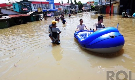   Sejumlah warga melintasi banjir di Jalan Dayeuhkolot, Kabupaten Bandung, Kamis(25/12).  (foto: Septianjar Muharam)