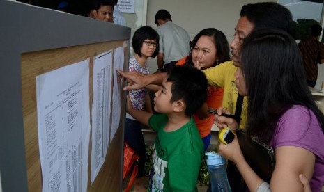   Keluarga penumpang pesawat Air Asia  penerbangan QZ 8501 melihat daftar nama penumpang di Crisis Center Center Air Asia  di Terminal 2 Bandara Juanda Surabaya di Sidoarjo, Jawa Timur, Ahad (28/12). (Antara/Suryanto)