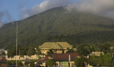   Sejumlah warga beraktivitas di depan Kedaton (keraton) Kesultanan Ternate dengan dengan latar belakang Gunung Gamalama di Kota Ternate, Maluku Utara, Ahad (28/12).  (Antara/Widodo S. Jusuf)