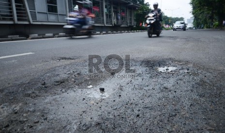 Kendaraan melintas di samping jalan yang berlubang di Jalan Otista, Jakarta Timur, Rabu (21/1).  (Republika/Raisan Al Farisi)