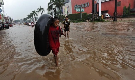 Seorang anak membawa ban ketika banjir melanda Kawasan Kelapa Gading Jakarta, Jumat (23/1).  (Antara/Wahyu Putro)     