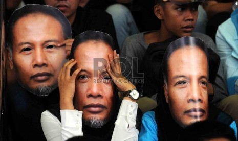  Piuluhan warga yang tergabung dalam Gerakan Rakyat Melawan Korupsi mengenakan topeng berwajah Wakil Ketua KPK, Bambang Widjojanto saat menggelar aksi di depan Gedung KPK, Jakarta, Sabtu (24/1). (Republika/Agung Supriyanto)