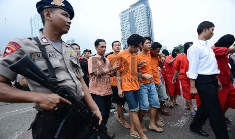 Seorang anggota kepolisian mengawal pelaku tindak kriminal