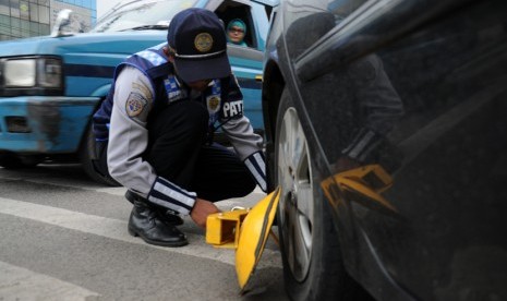   Petugas Dishub Kota Depok membuka gembok pada mobil yang telah digembok sejak pagi karena parkir sembarangan di Jalan Raya Margonda, Depok, Senin (16/3).   (foto : MgROL_34)